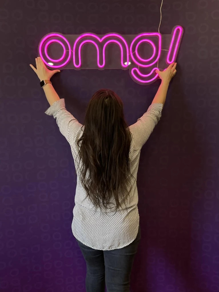 The OMG! neon sign on a purple wall